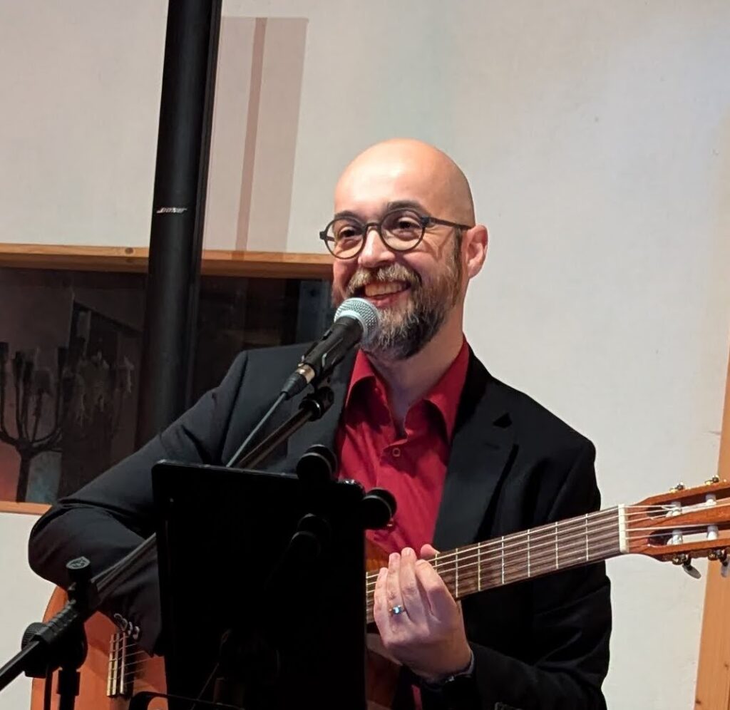 Chorleiter mit Gitarre und Mikrophon